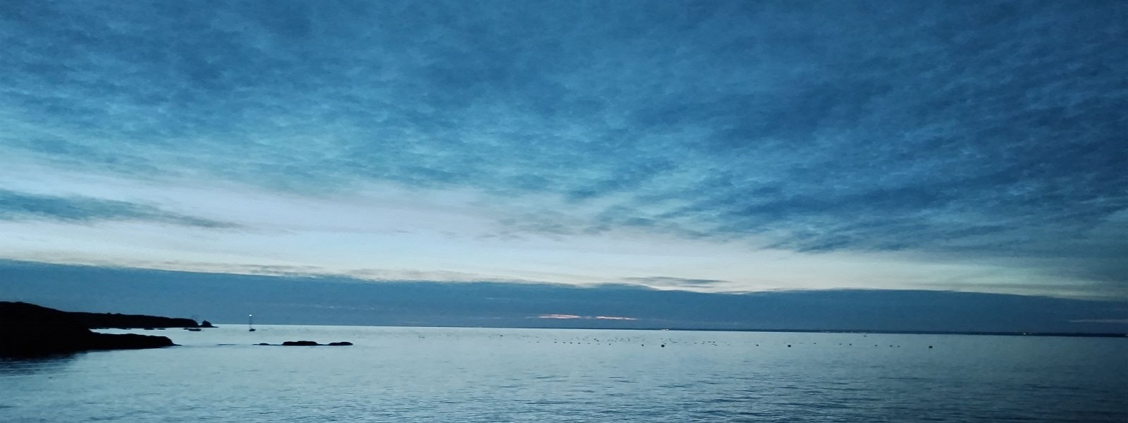 Horizon marin calme au crépuscule, ciel bleu et mer paisible.